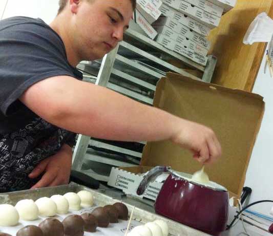 Junior Sean Shadle dips cake balls for an upcoming order. | lauren sanders photo