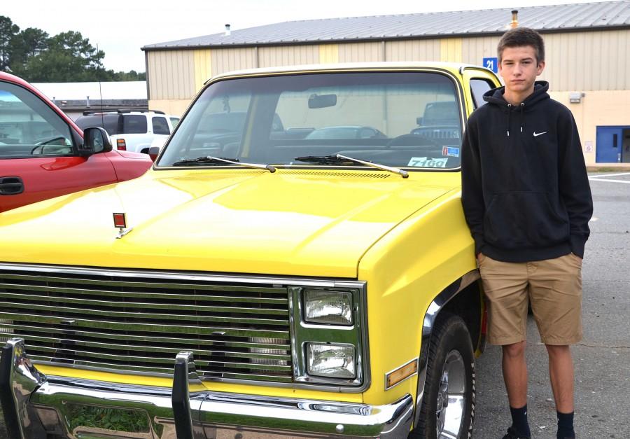 sophomore Dylan Gillespie leans on his 1984 GMC Seirra 