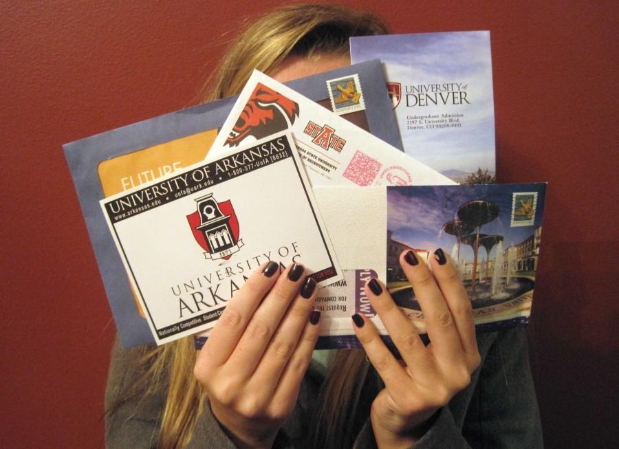 With college flyers in hand, a student shows off different college options for seniors.