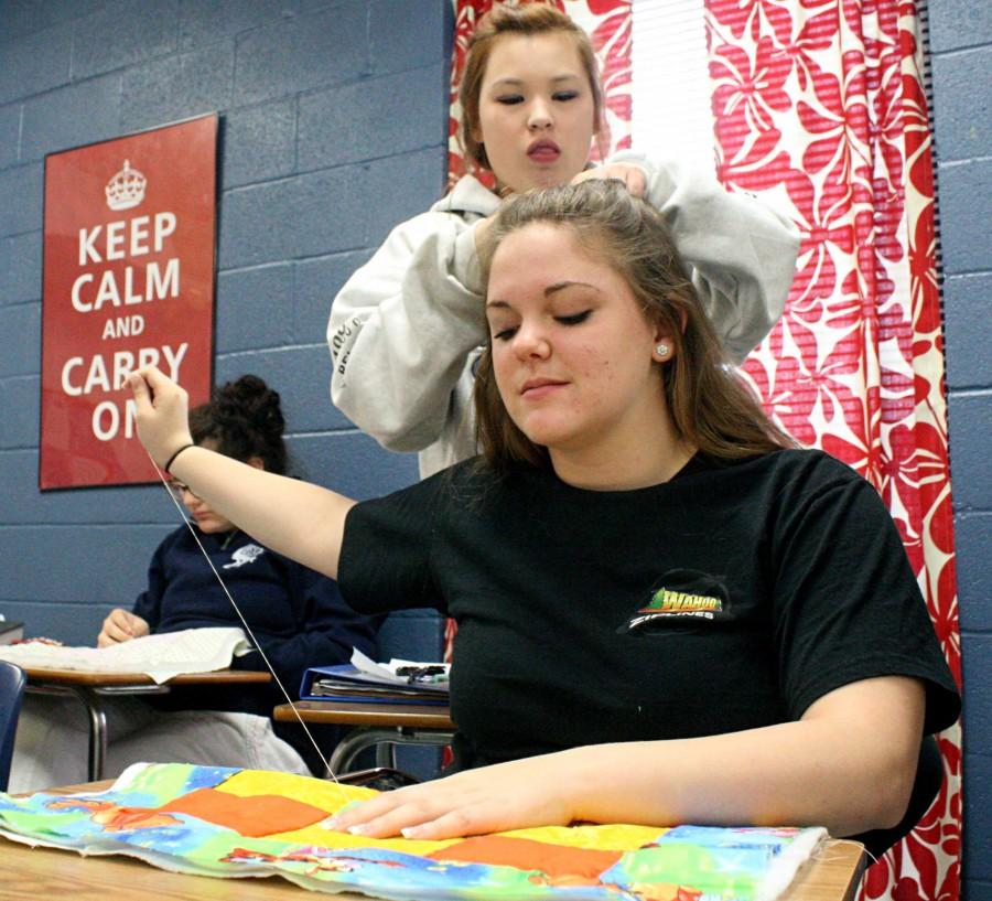 While getting her braided by senior Sara Anderson, junior Devin Hester sews her pillow | Baylie McLaren photo