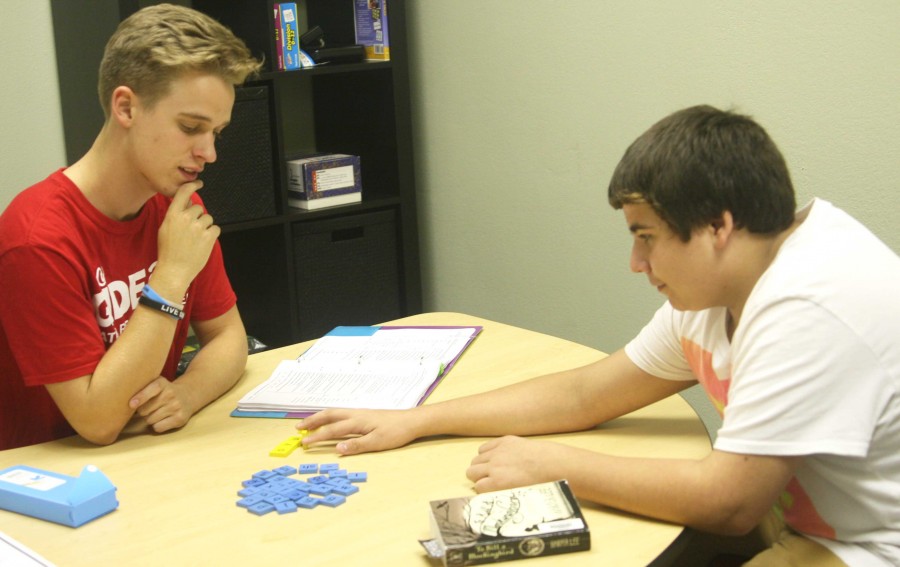 Surrounded by tiles and paper, senior Caleb Zimmerman tutors students at Gideon Math and Reading. | photo Autumn Pruett