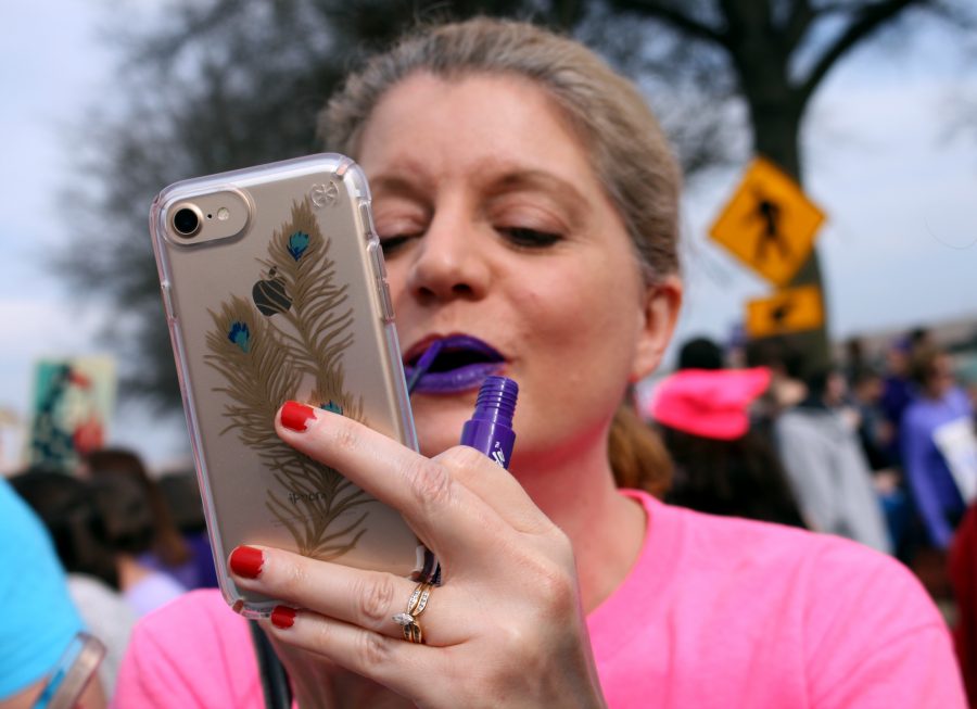 Senior Julia Nalls mother, Deana Nall, applies senior Emma Goads purple lipstick to fit the theme of the march. Nall has previously been involved with the Bryant Young Democrats chapter and provided support at the march.