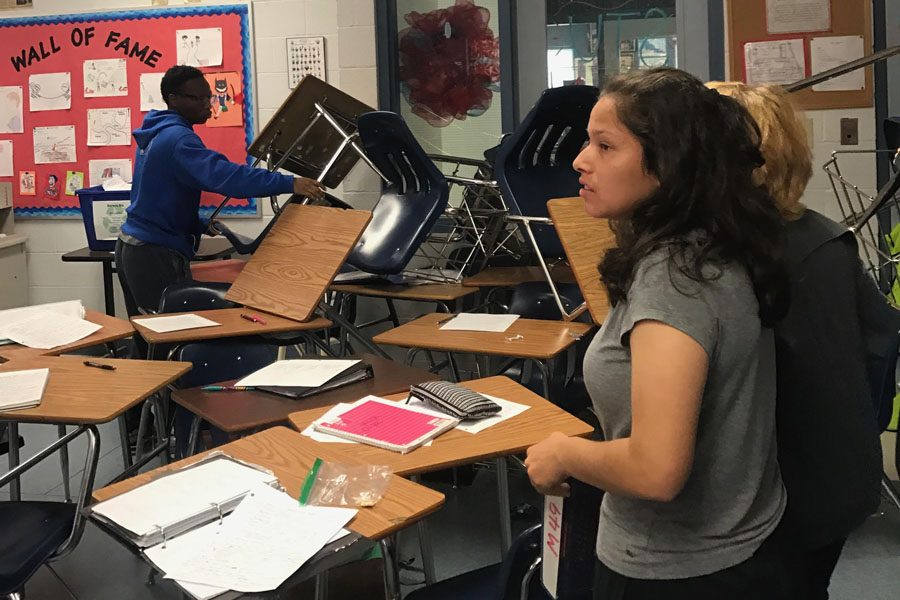 Juniors Dionte Collier and Katheryn VIvar barricade the door in AP U.S. History teacher Amber Leatons room during a false alarm lockdown April 6. The alarm was accidentally triggered by a teacher using the Rave Panic Button app. | Photo Abby Hagner