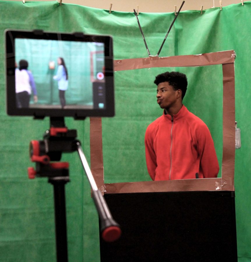 Standing behind a television crafted from paper and a metal frame, sophomore Jordan Hunter watches the director set up the next scene. Hunter took the role after being encouraged by classmates.