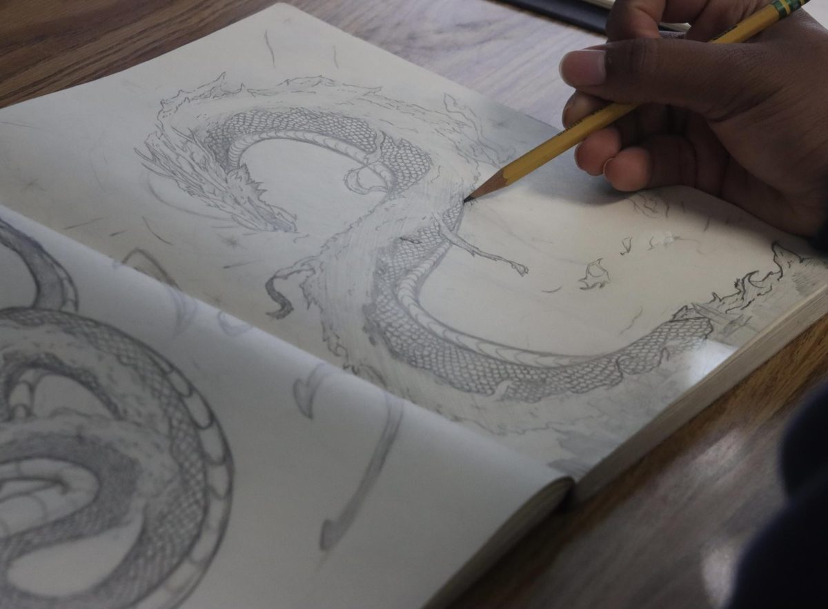 Sophomore Demarius Zachary sketches a dragon during a Buzz Time session dedicated to Art and Sketching competitions. Zachary focuses on adding and perfecting details in the sketch in an effort to win the competition. 
