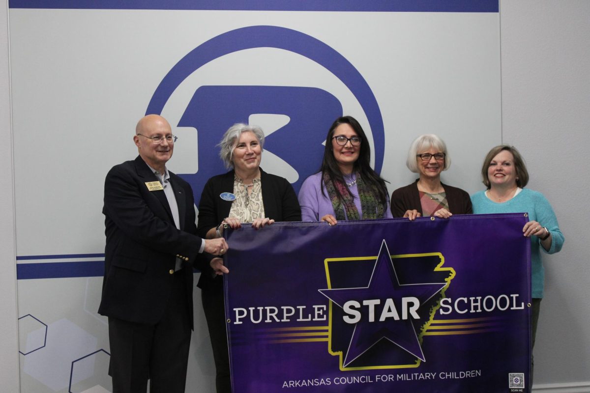 John Kaminar presents the Purple Star School banner to counselors Amy Oury and Brenda Rogers.