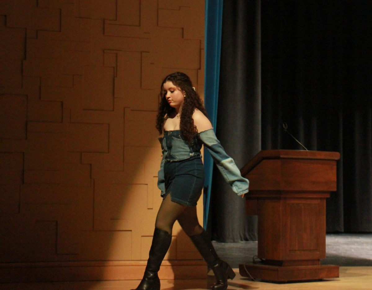 Senior Maya Boughamrani heads to the side of the stage after her walk out. Senior Emeril Jones made Boughamrani top and Mrs. Purcell allowed her to borrow some boots to pull her outfit together. 