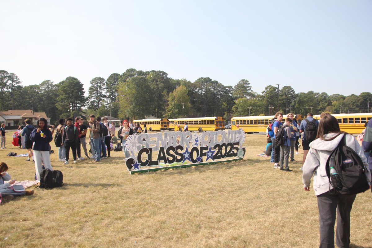 Senior students search for their friends and the perfect picnic spot in the bus loop field as the “Senior Picnic Class of 2025” sign stands tall in the center. This was the very beginning of the picnic.