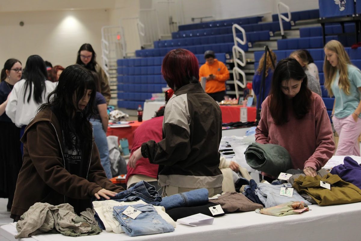 Sophomores Giselle Giron, Miles Cheatham and Teya Romero market thrifted clothes from fellow students for the fashion club. 