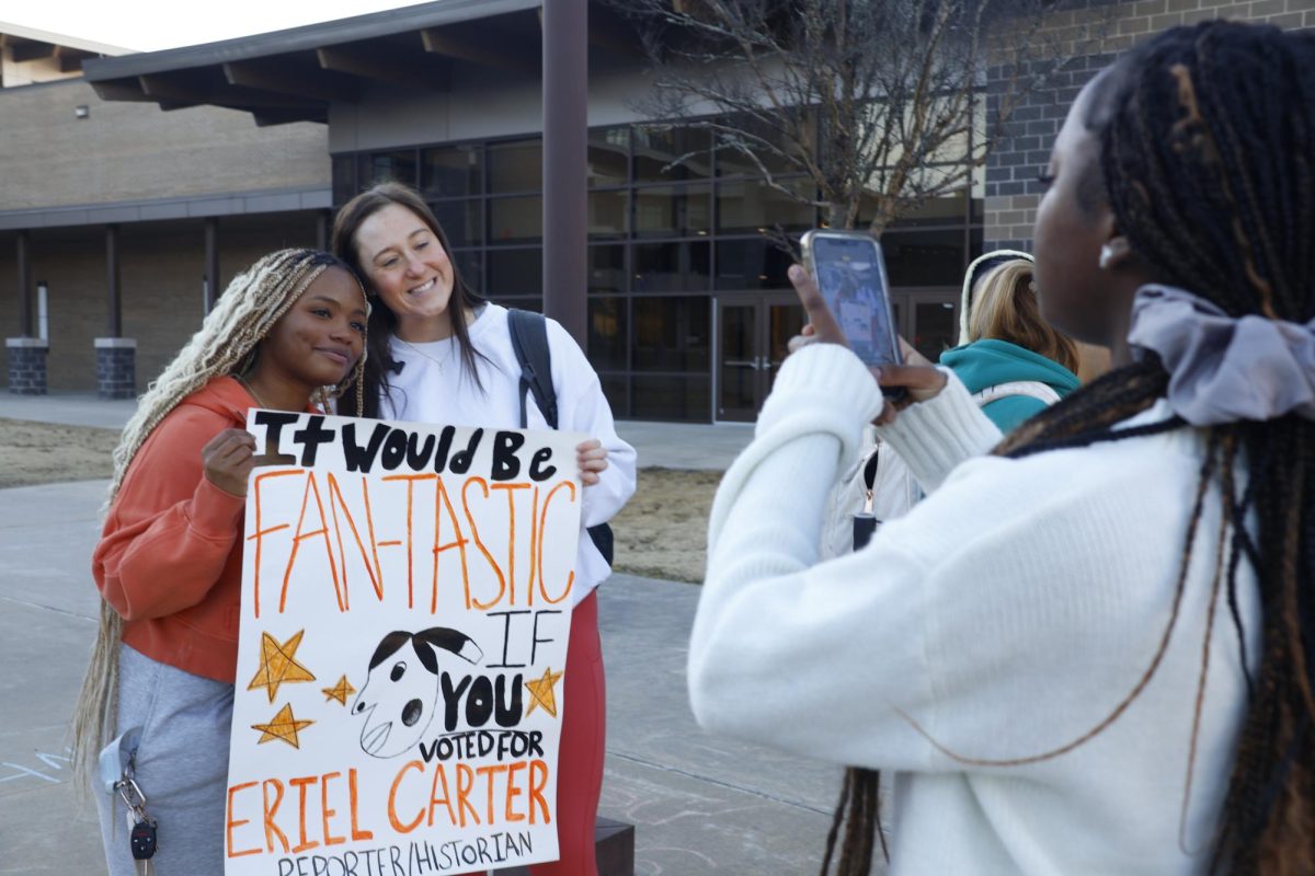 Ja'Lill Trice takes photo of Eriel Carter and Braleigh Thornton while holding up a campaign sign.