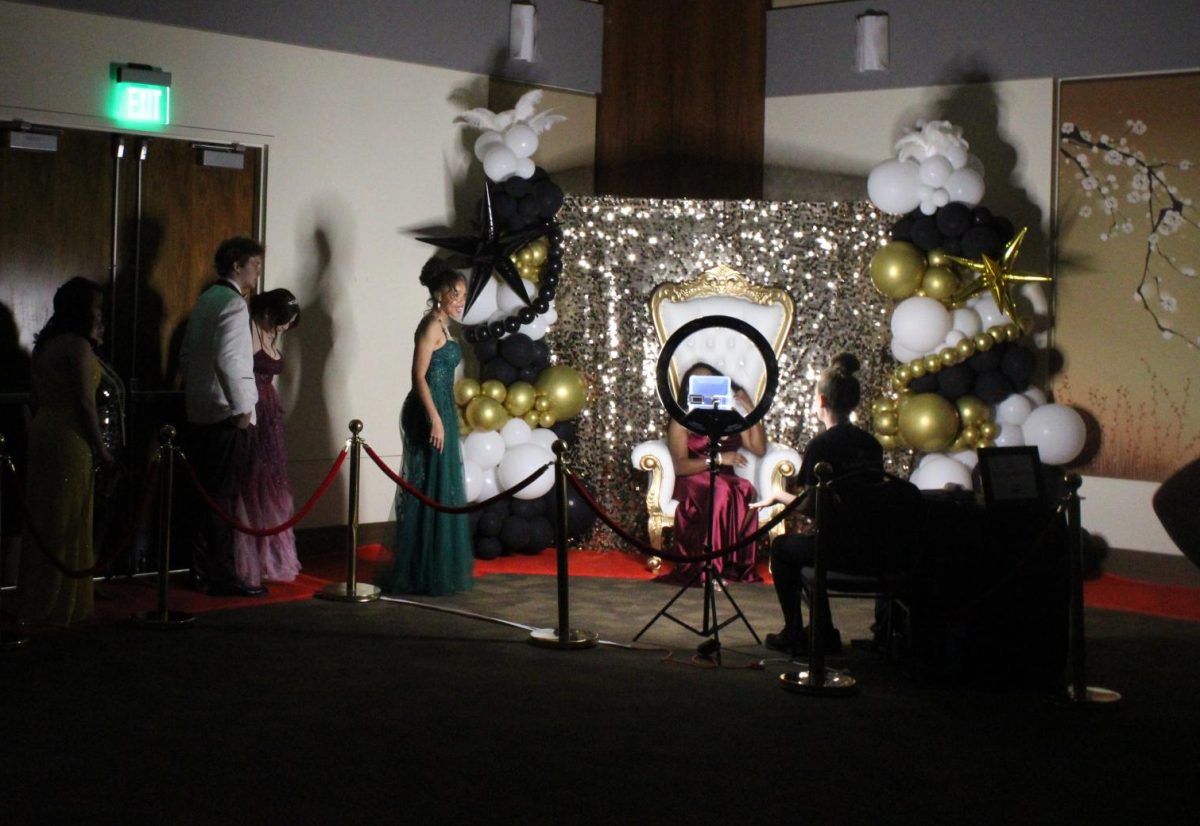 Prom participants wait in line to pose for photos in the “Great Gatsby Chair” in the ballroom of the Benton Event Center.
