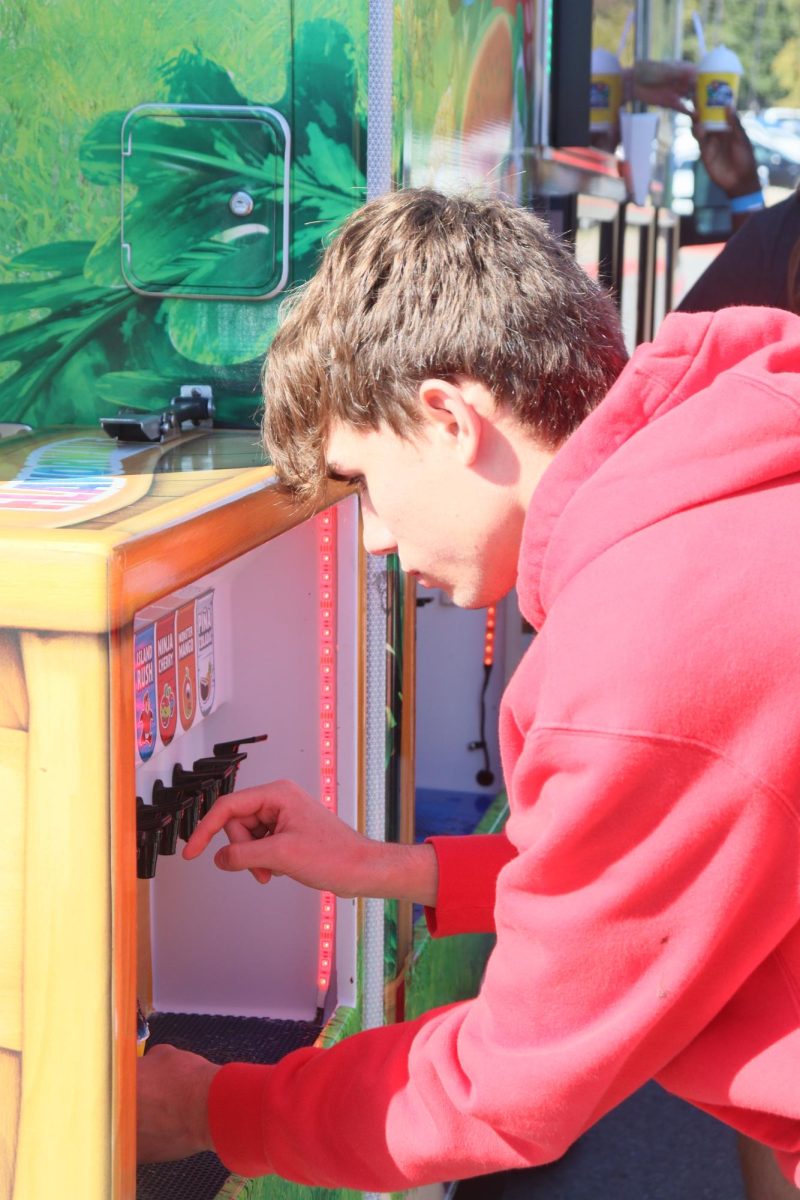 Senior Devin Hogue adding flavor to his snow cone from the Kona Ice truck during Senior Picnic. 