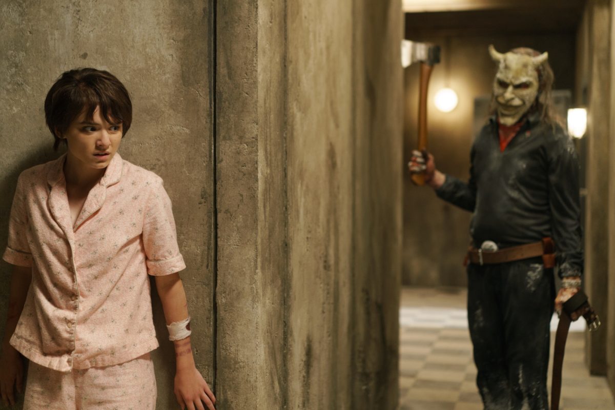 A scene from “Black Phone 2” showing a tense moment between Gwen and the masked kidnapper, known as The Grabber. They are in the basement where Finney was kidnapped and held in “The Black Phone”.