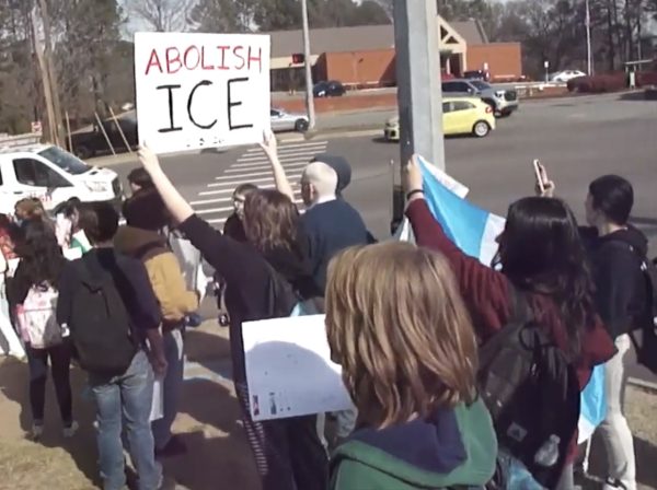 Participants in the anti-ICE walkout marching together down North Reynolds Road with their handmade signs. 